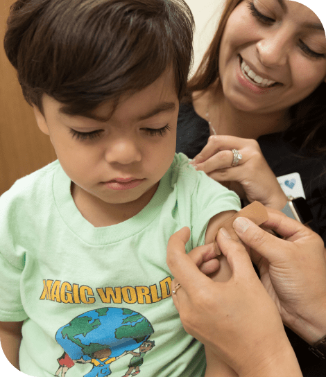 A nurse putting a band-aid on a child’s arm.
