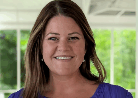 Kari Brandford smiles at the camera, wearing a blue blouse.